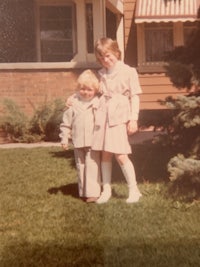 two children standing in front of a house