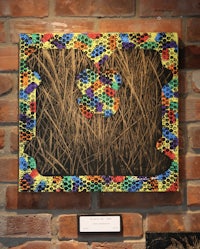 a colorful piece of art hanging on a brick wall