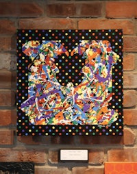 a colorful painting hanging on a brick wall